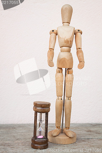 Image of Wood mannequin and hourglass to represent time over 