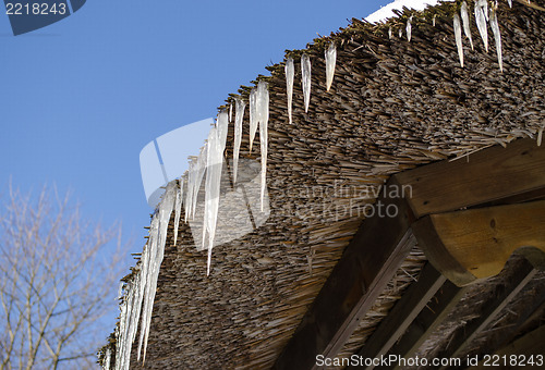 Image of small icicles retro straw roof background blue sky 