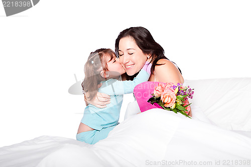 Image of Child gives flowers and kiss to mom in bed
