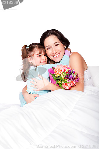 Image of Child gives flowers to mother in bed