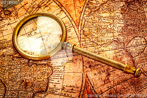 Image of Vintage magnifying glass lies on an ancient world map