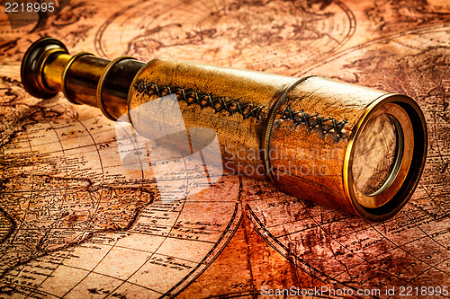 Image of Vintage spyglass lies on an ancient world map