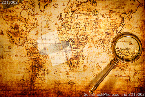 Image of Vintage magnifying glass lies on an ancient world map