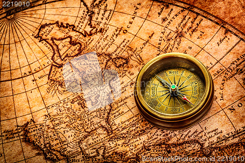 Image of Vintage compass lies on an ancient world map.