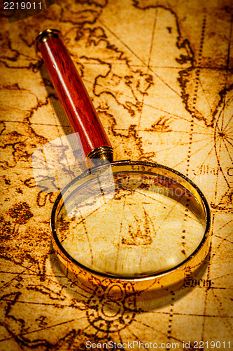 Image of Vintage magnifying glass lies on an ancient world map