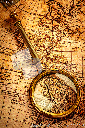 Image of Vintage magnifying glass lies on an ancient world map