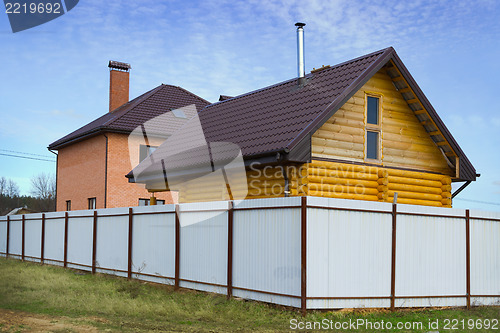 Image of Brick and wooden house behind a fence