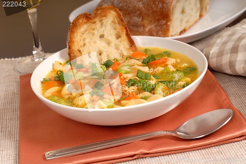 Image of Bowl of chicken noodle soup with rustic bread and a glass of win