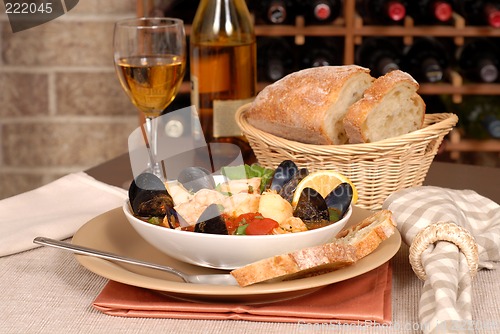 Image of Bowl of seafood soup with wine and rustic bread