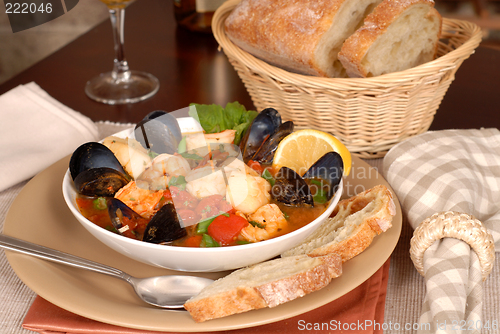 Image of Bowl of delicious seafood soup with wine and rustic bread