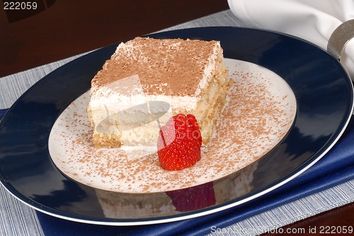 Image of A piece of tiramisu dusted with cocoa on a blue plate