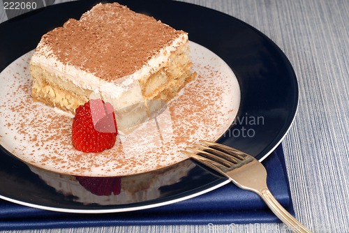 Image of A piece of tiramisu dusted with cocoa with a fork on a blue plat