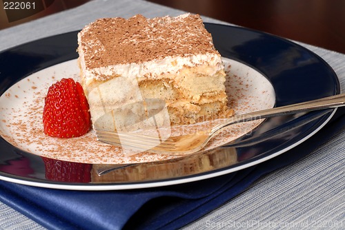 Image of Side view of a piece of tiramisu dusted with cocoa with a fork o