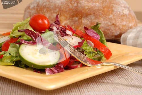 Image of Side view of a healthy salad on a yellow plate with rustic bread