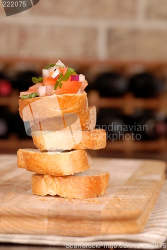 Image of Stack of bruschetta with wine rack in background