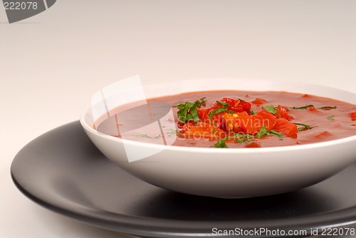 Image of Tomato, red pepper, basil soup in white bowl with light gray bac