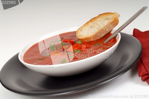 Image of Tomato, red pepper, basil soup in white bowl with bread and spoo