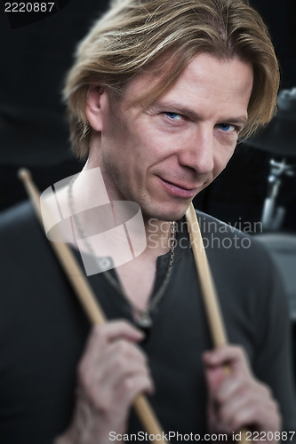 Image of Man with drum sticks is looking to the viewer