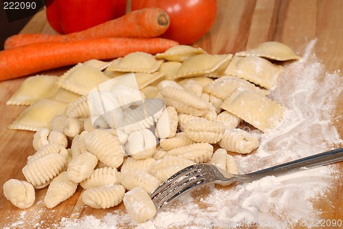 Image of Gnocchi and ravioli on a floured cutting board with vegetables i