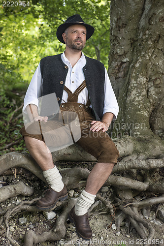 Image of Seated man in traditional Bavarian costumes in forest