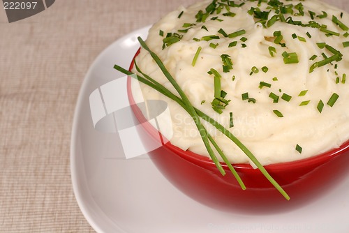 Image of Closeup of creamy mashed potatoes with chives in a red bowl