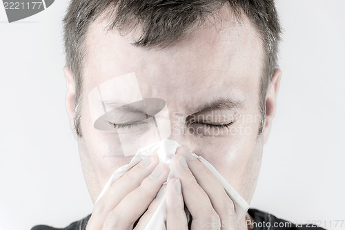 Image of Ill man with tissue is sneezing