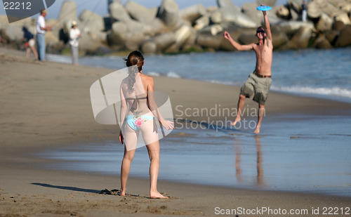 Image of Couple playing frisbee on the beach