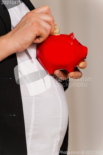 Image of Pregnant business woman with piggy bank