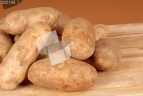 Image of Several russet potatoes piled on a cutting board