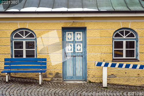 Image of Yellow house with blue bench