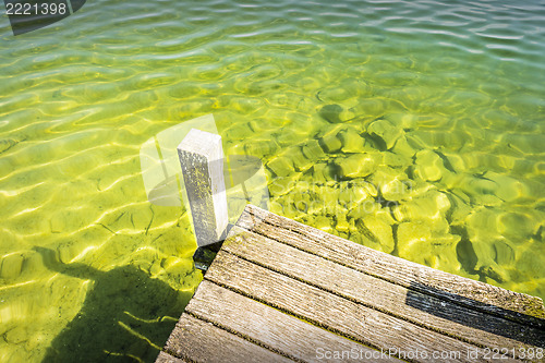 Image of Part of a jetty over a lake of weathered wood with green-blue wa