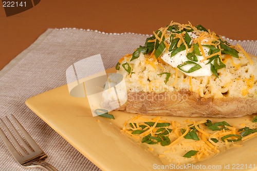Image of A twice baked potato with scallions, cheese and sour cream