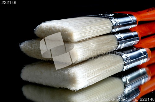 Image of three stacking paint brushes with reflection on table