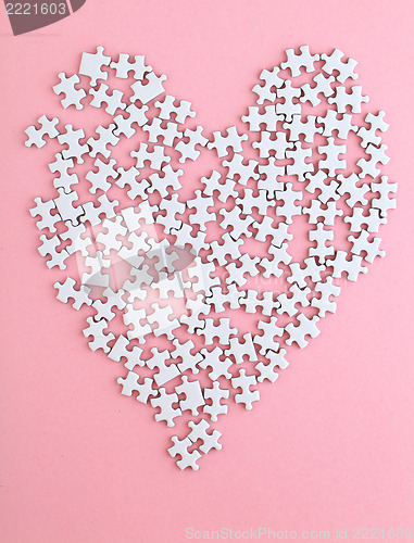 Image of puzzle made heart shape on pink background