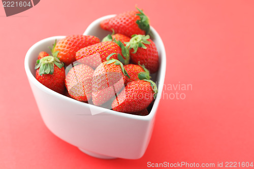 Image of Strawberry in heart shape bowl on red background