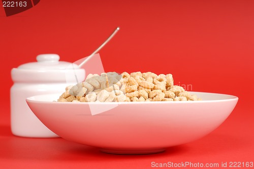 Image of Bowl of oat cereal with sugar bowl on red background