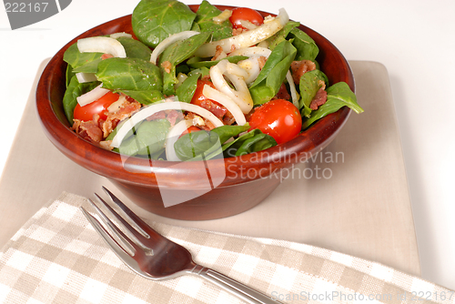 Image of Fresh spinach salad in a brown wooden bowl