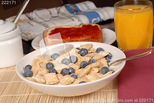 Image of Wheat cereal with blueberries, toast, orange juice and newspaper
