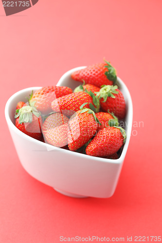 Image of Strawberry in heart shape bowl on red background