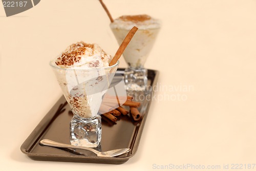 Image of Two glasses of rice pudding with cinnamon on a black tray