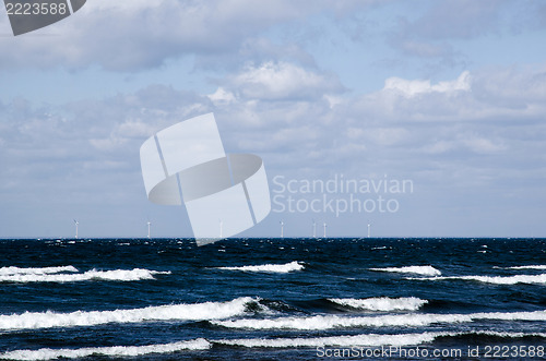 Image of Waves with windmills in the horizon