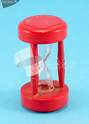 Image of broken red sand glass clock on blue background 