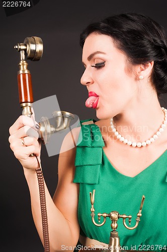 Image of Attractive woman showing tongue into phone