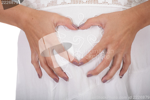 Image of Woman holding her hands in a heart shape on her pregnant belly