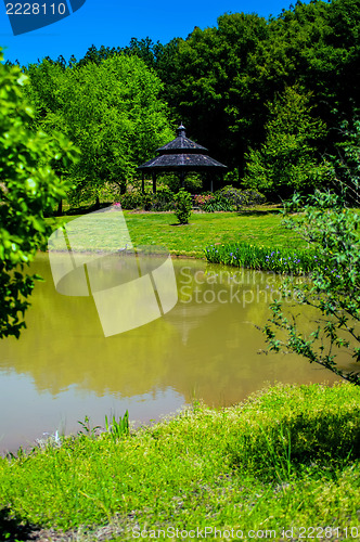Image of water reflects nature with gazebo in distance