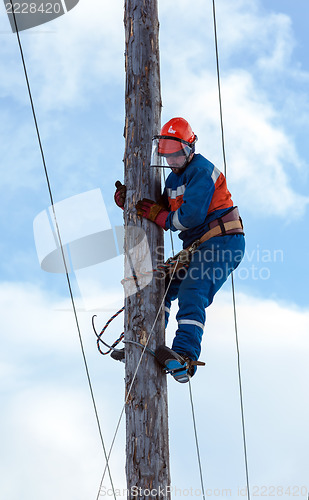 Image of electrician climbs a power pole