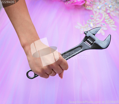 Image of Hand of bride holding a big wrench