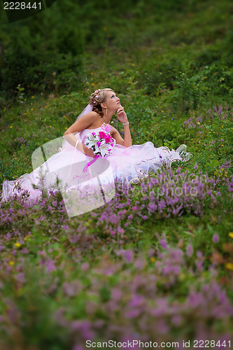 Image of Young beautiful bride sitting at a forest glade