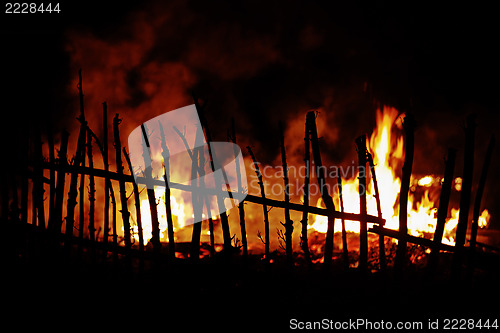 Image of Fire in countryside with wooden fence in foreground