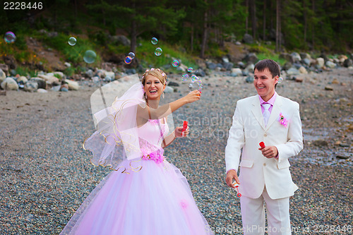 Image of Bride and groom having fun with soap bubbles